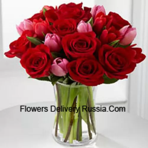 11 roses rouges et 6 tulipes roses avec quelques garnitures saisonnières dans un vase en verre
